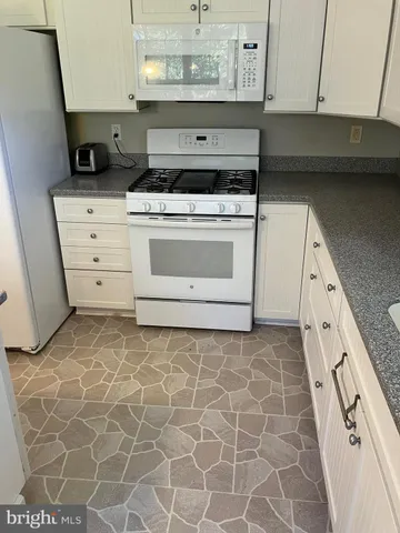 a kitchen with granite countertop a stove top oven a sink a microwave and cabinets