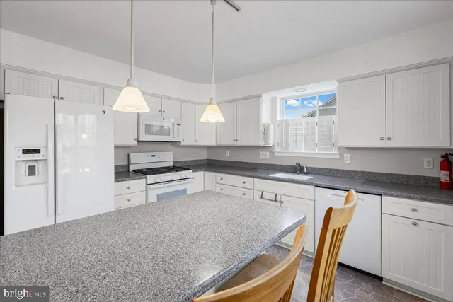 a kitchen with stainless steel appliances granite countertop a sink a stove a refrigerator a center island and cabinets