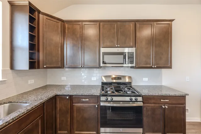 a kitchen with granite countertop wooden cabinets and stainless steel appliances