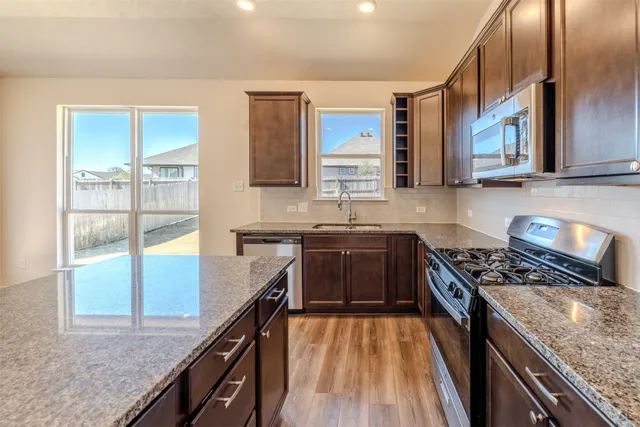 a kitchen with granite countertop a stove a sink and a cabinets