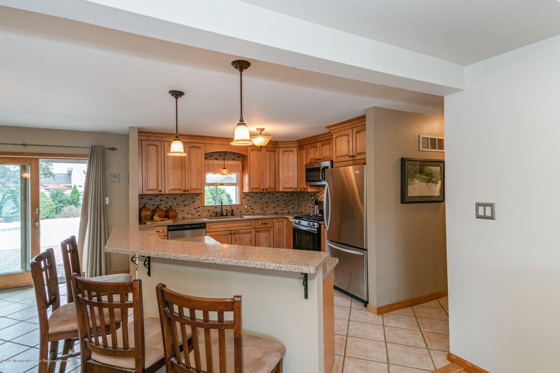 132 Mizzen Road Brick, NJ 08723 - Photo 9 of 41 a kitchen with stainless steel appliances granite countertop a refrigerator a stove a sink a dining table and chairs with wooden floor