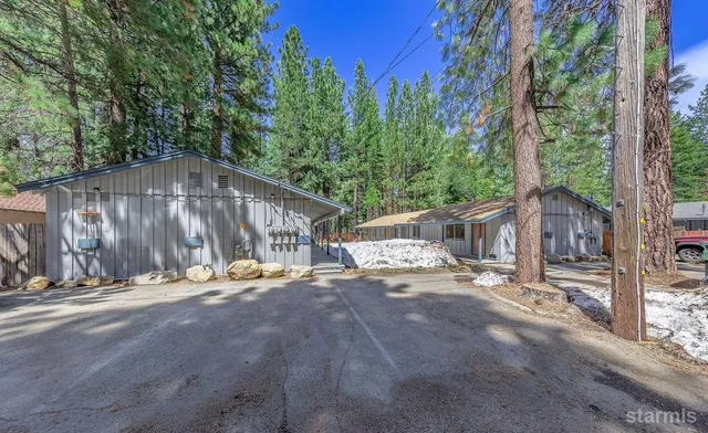 a backyard of a house with table and chairs under an umbrella