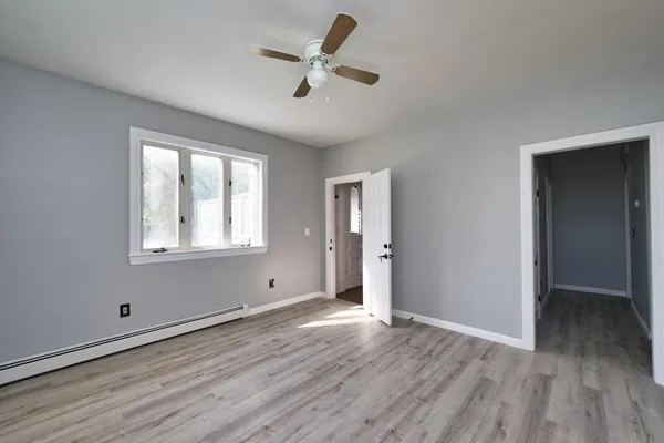 an empty room with wooden floor fan and windows