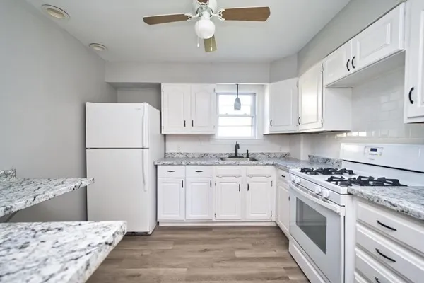 a kitchen with stainless steel appliances granite countertop a stove a refrigerator a sink and white cabinets