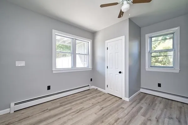 a view of empty room with wooden floor and fan