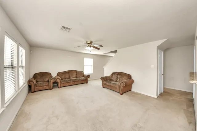 an empty room with windows and chandelier fan