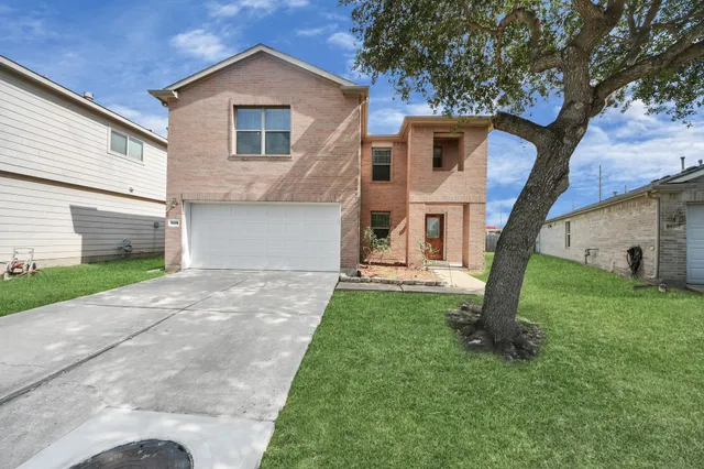 a view of a house with a yard and a large tree