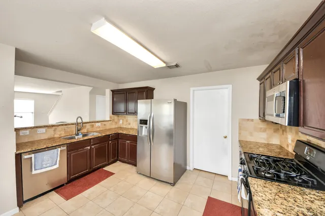 a kitchen with stainless steel appliances granite countertop a refrigerator and a stove