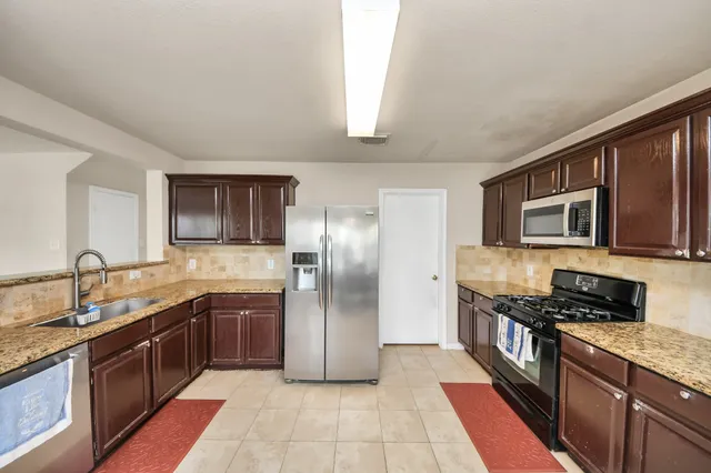 a large kitchen with stainless steel appliances granite countertop a refrigerator and a sink
