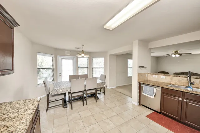 a dining hall with stainless steel appliances granite countertop a stove a sink a dining table and chairs with wooden floor