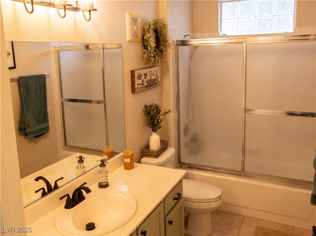 2050 West Warm Springs Road, Unit 411 Henderson, NV 89014 - Photo 17 of 30 Full bathroom featuring vanity, combined bath / shower with glass door, tile patterned flooring, and toilet