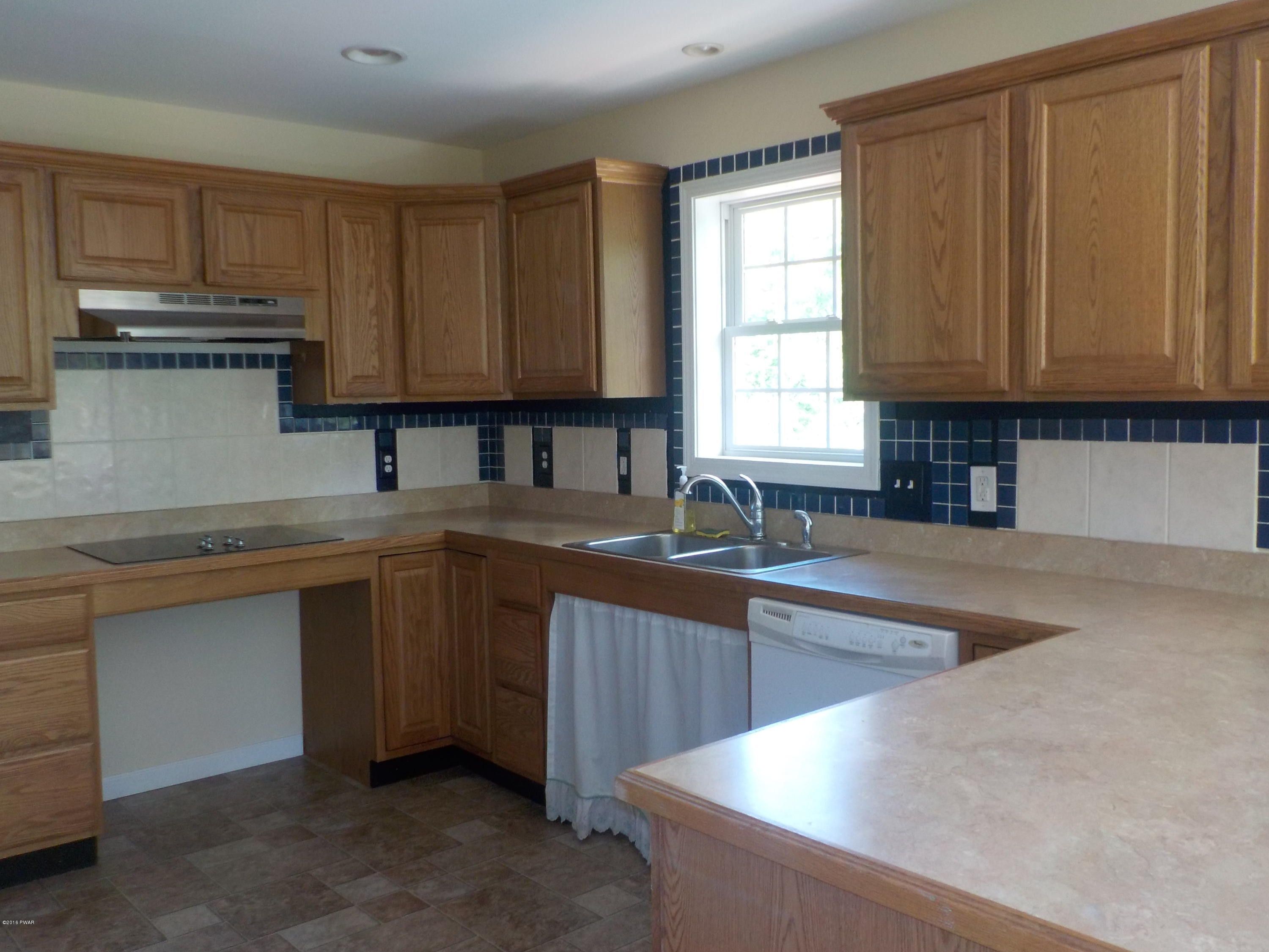230 Maple Ridge Drive Hawley, PA 18428 - Photo 8 of 35 a kitchen with kitchen island granite countertop a sink window and cabinets