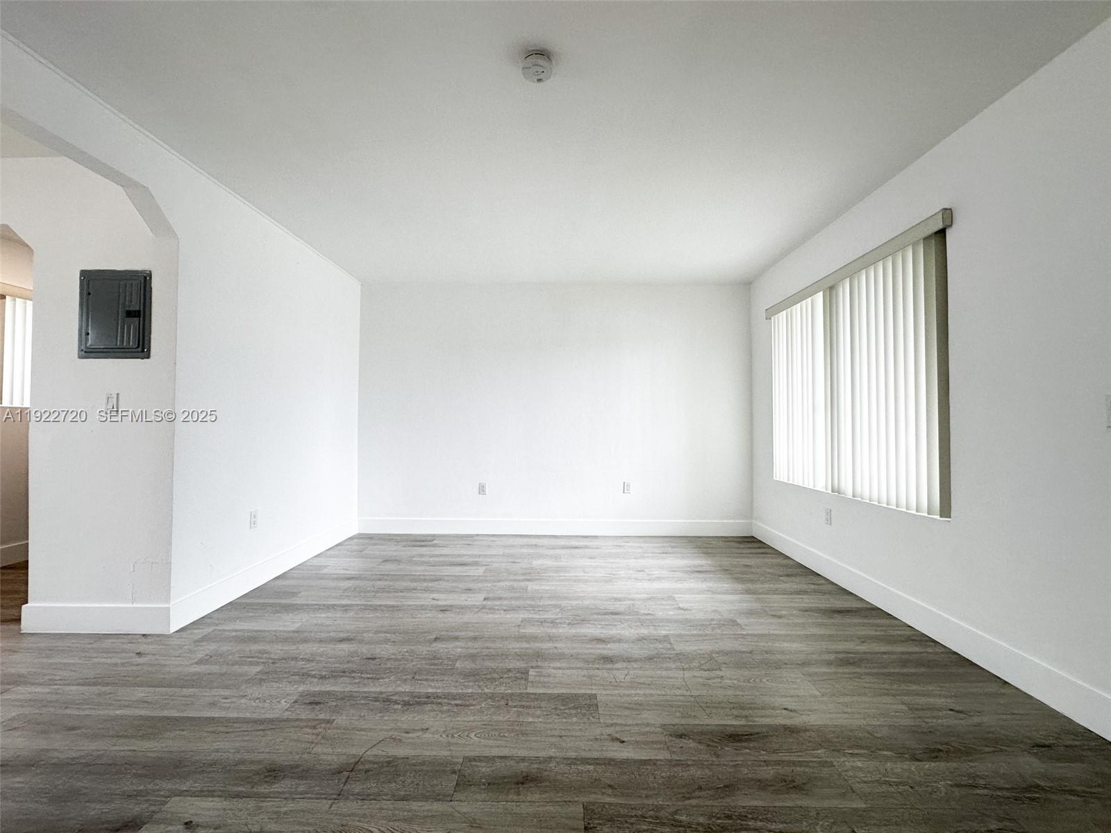 1894 Northwest 53rd Street, Unit A Miami, FL 33142 - Photo 2 of 10 an empty room with wooden floor and windows