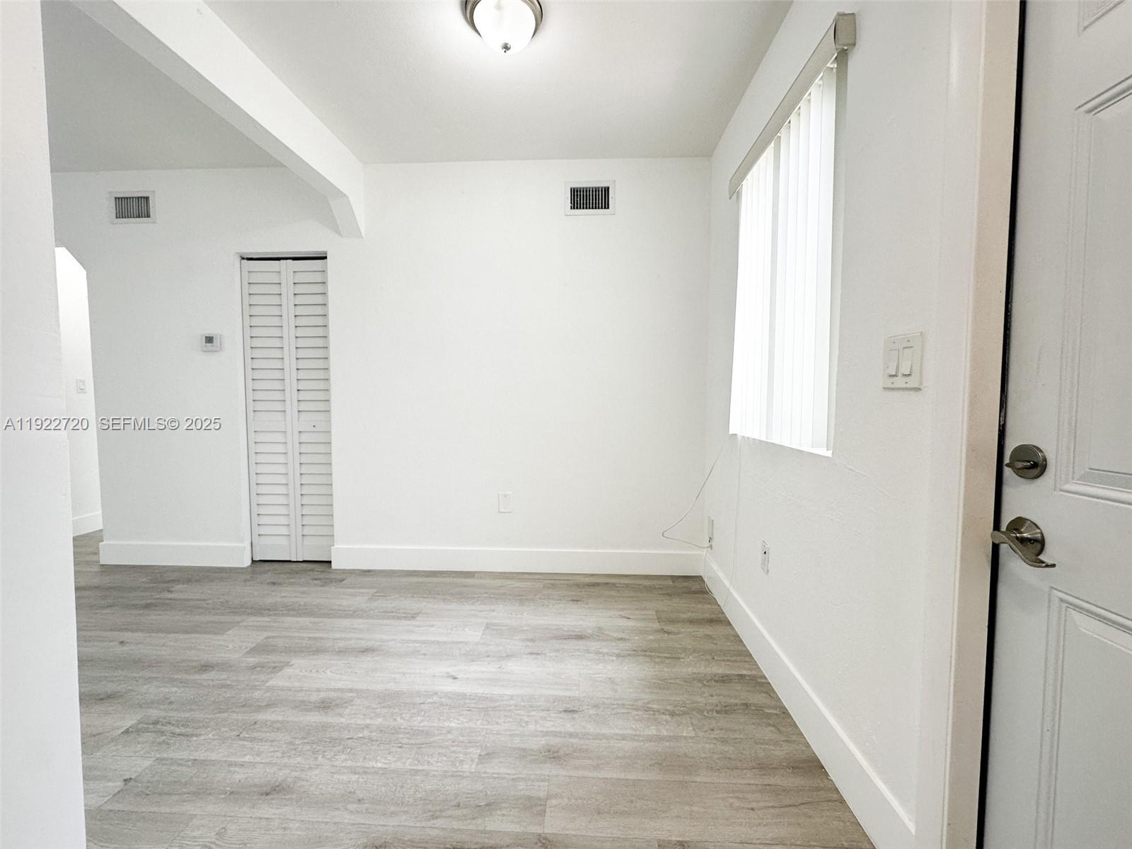 1894 Northwest 53rd Street, Unit A Miami, FL 33142 - Photo 4 of 10 a view of an empty room with wooden floor and a window