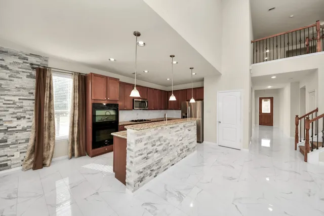 a open kitchen with stainless steel appliances kitchen island granite countertop a refrigerator and a sink