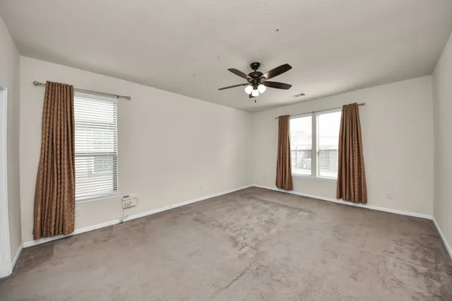 an empty room with windows and ceiling fan