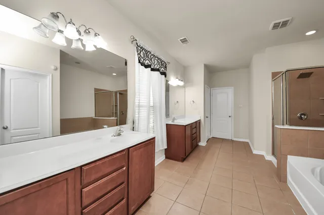 a spacious bathroom with a tub sink and mirror