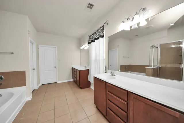 a spacious bathroom with a sink a large mirror and a bathtub