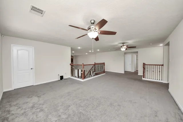 an empty room with ceiling fan and windows