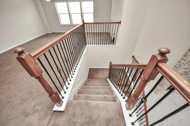a view of staircase with railing and white walls