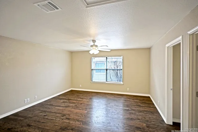 an empty room with wooden floor chandelier and windows