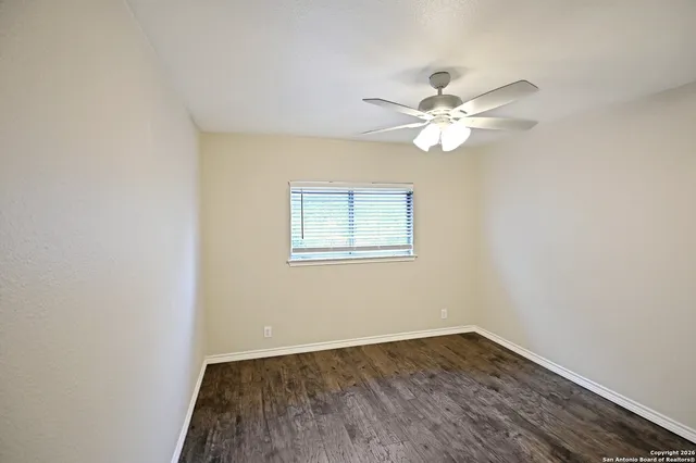 an empty room with a window and a fan