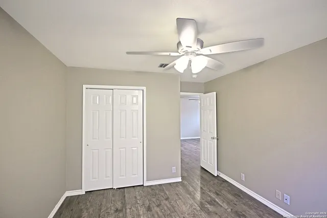 an empty room with closet and a ceiling fan