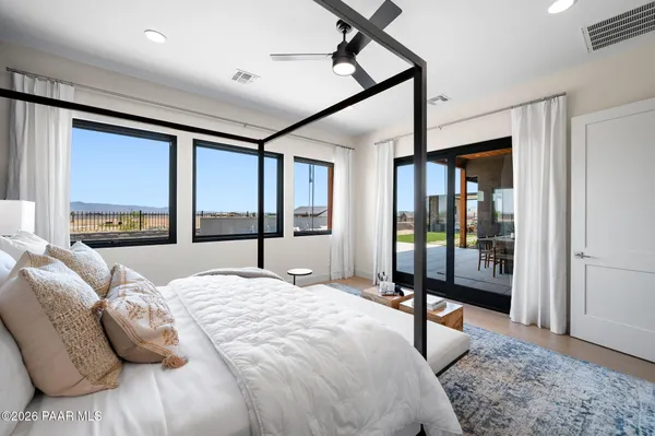 a bedroom with a bed large window and a flat tv screen