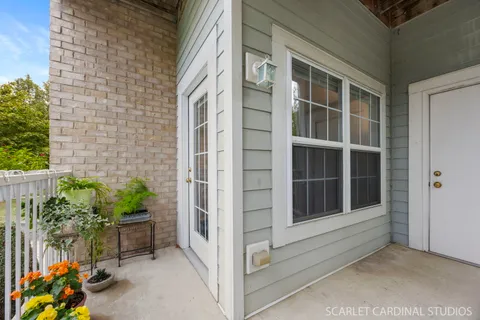 a view of a balcony with potted plants and floor to ceiling window and wooden fence