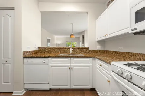 a kitchen with granite countertop white cabinets and a stove