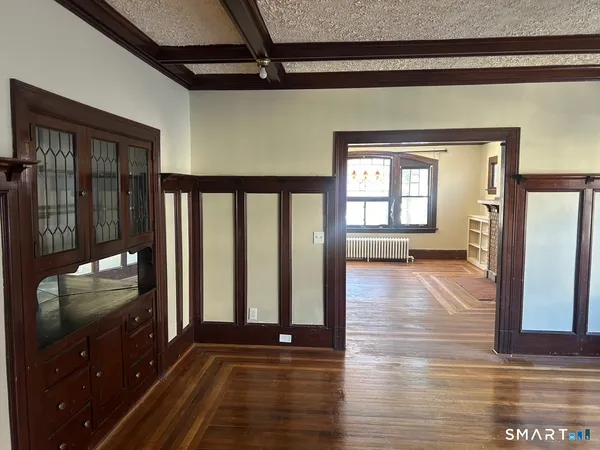 a view of an empty room with wooden floor and a window