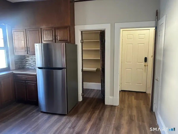 a kitchen with a refrigerator and wooden floor