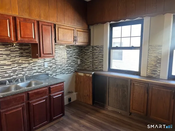 a kitchen with granite countertop a sink wooden cabinets and a window
