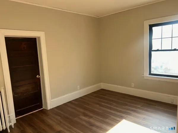 an empty room with wooden floor closet and windows