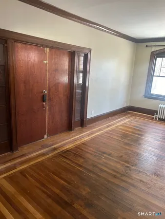 a view of an empty room with window and wooden floor