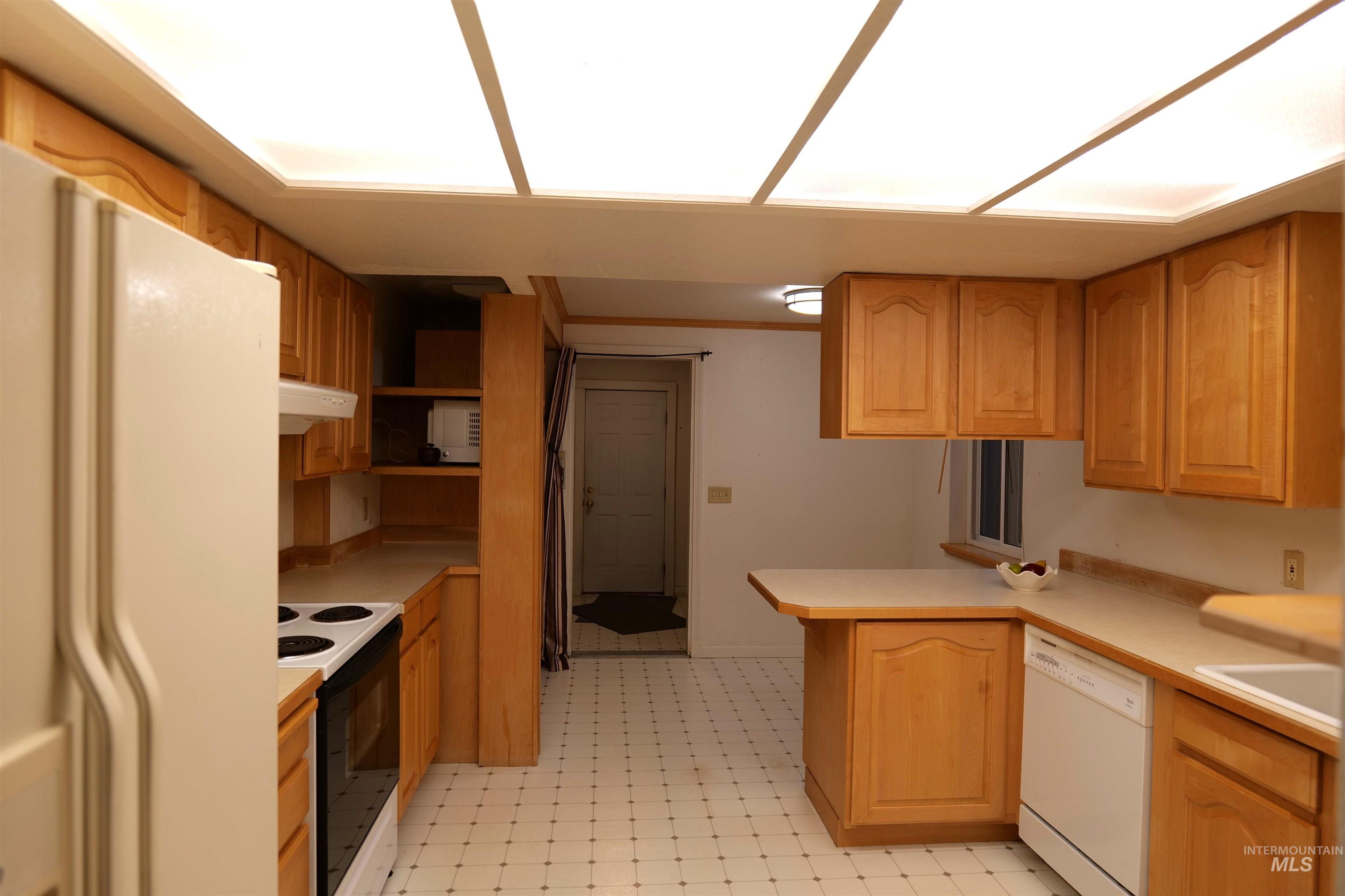 1485 East 9th Street Weiser, ID 83672 - Photo 2 of 18 Kitchen featuring wood cabinetry, white appliances, a patterned floor, and a built-in breakfast bar