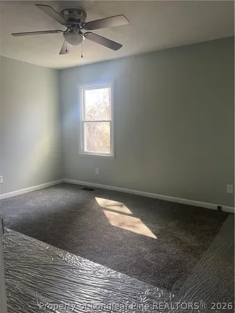 an empty room with a ceiling fan and window