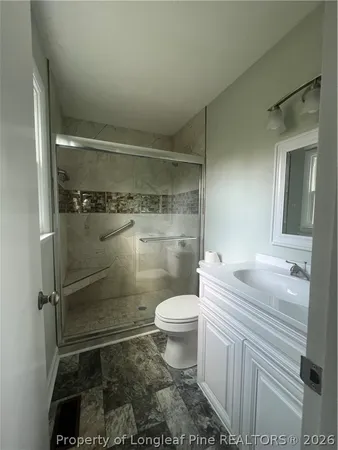 a bathroom with a granite countertop toilet a sink and shower