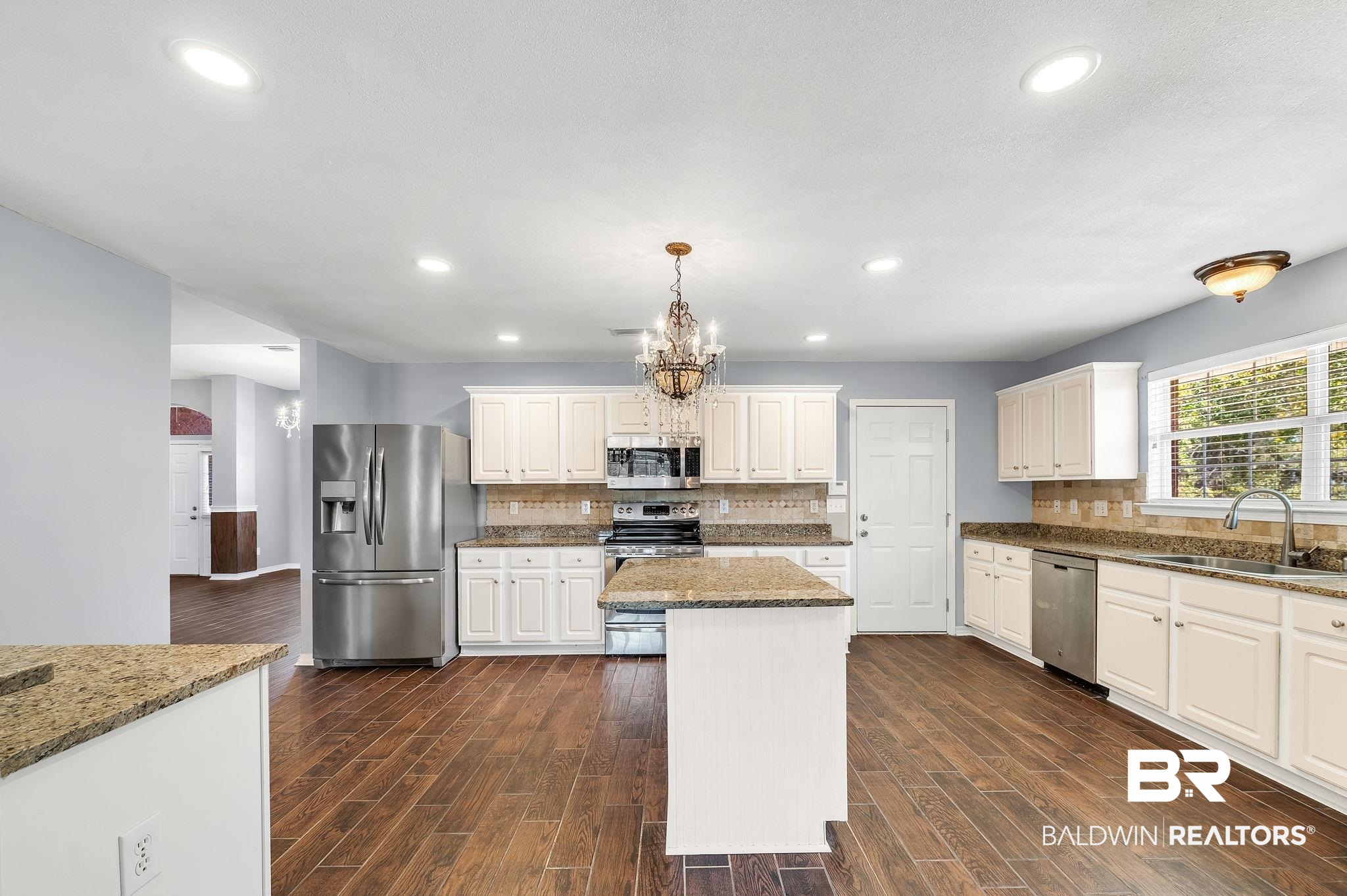 16444 Hamlet Lane Foley, AL 36535 - Photo 19 of 49 Kitchen with a sink, appliances with stainless steel finishes, dark wood-style flooring, dark stone countertops, and an inviting chandelier