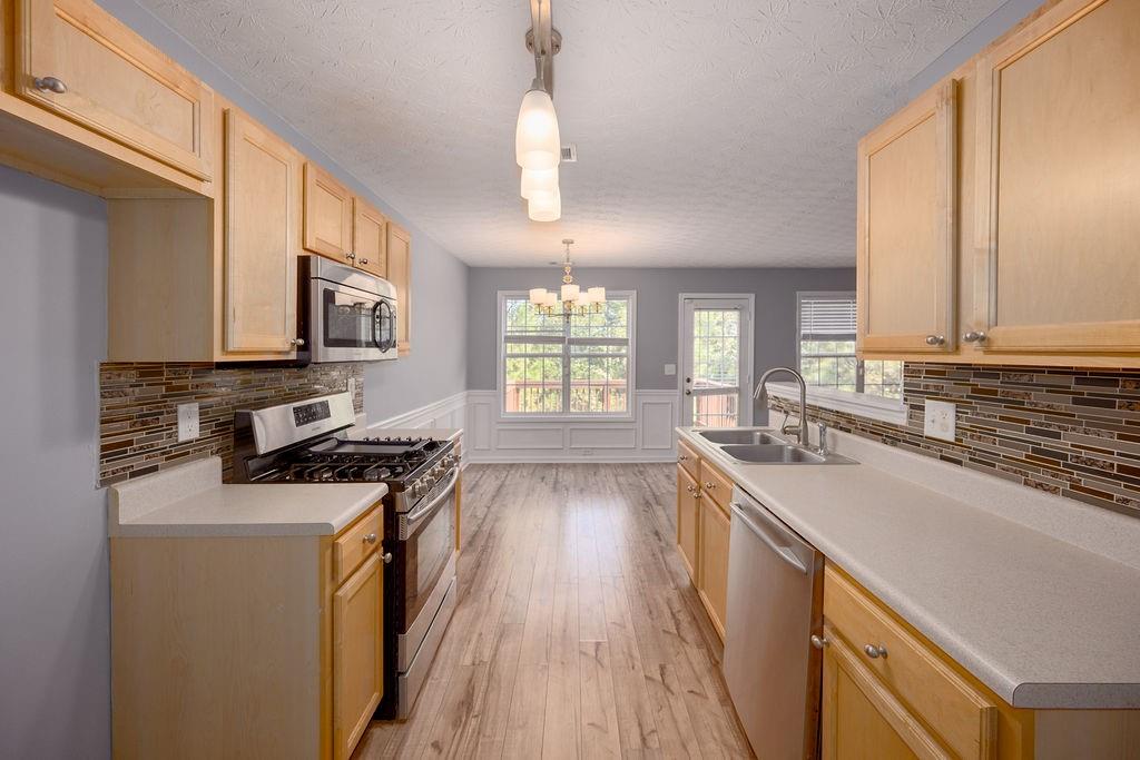 6280 Lake Valley Point Lithonia, GA 30058 - Photo 6 of 30 a kitchen with a sink a stove cabinets and a wooden floor