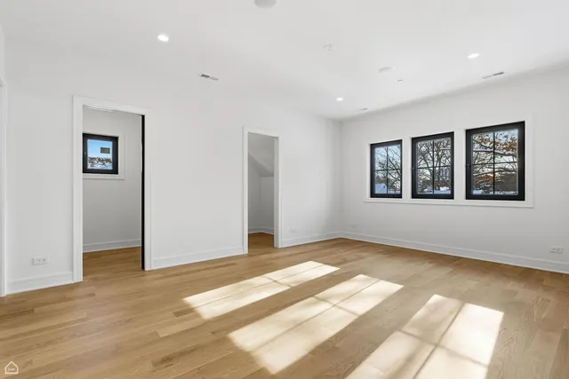 a view of an empty room with window and wooden floor
