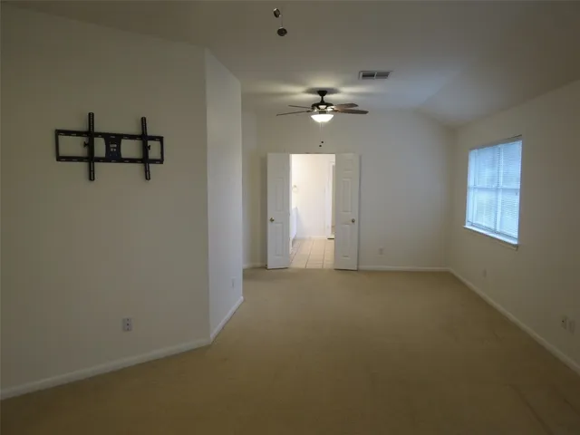 an empty room with windows and ceiling fan