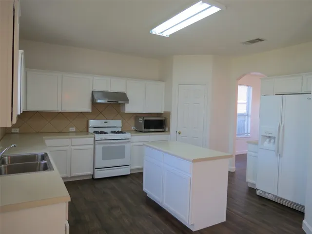 a kitchen with granite countertop white cabinets and white appliances
