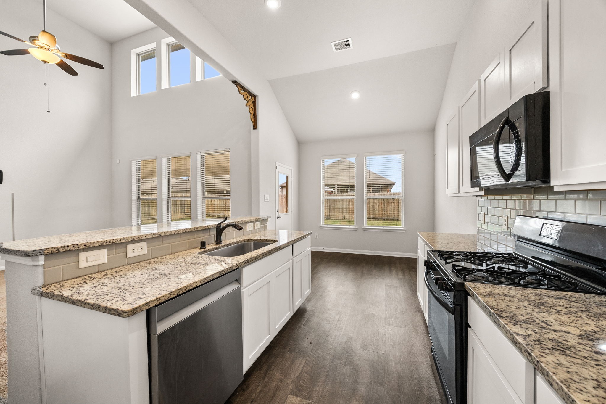 15731 Ty Cobb Court Splendora, TX 77372 - Photo 14 of 36 a kitchen with granite countertop stainless steel appliances a sink stove and cabinets