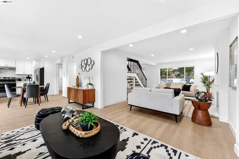 a living room with furniture a rug kitchen view and a chandelier