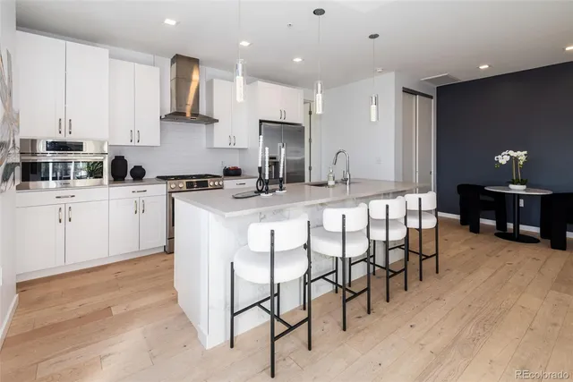 a kitchen with stainless steel appliances granite countertop a table chairs sink and cabinets