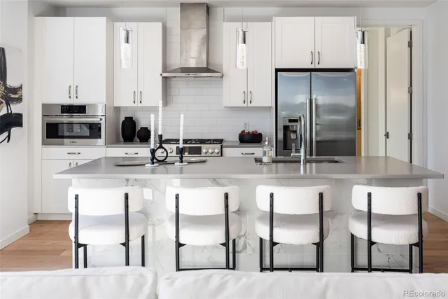 a kitchen with stainless steel appliances kitchen island granite countertop a table chairs refrigerator and sink