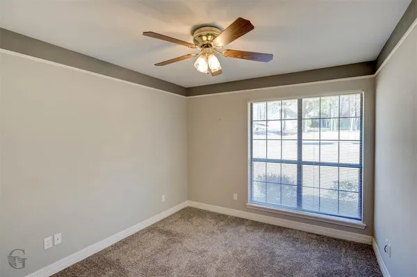 an empty room with window and ceiling fan