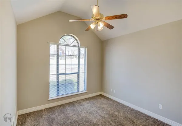 an empty room with windows and ceiling fan