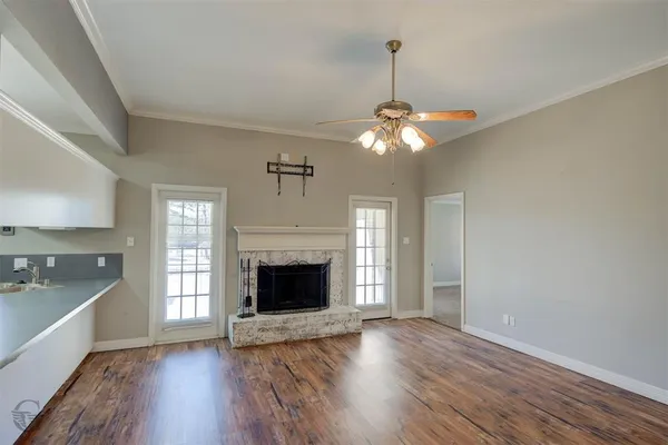 a view of an empty room with wooden floor fireplace and a window